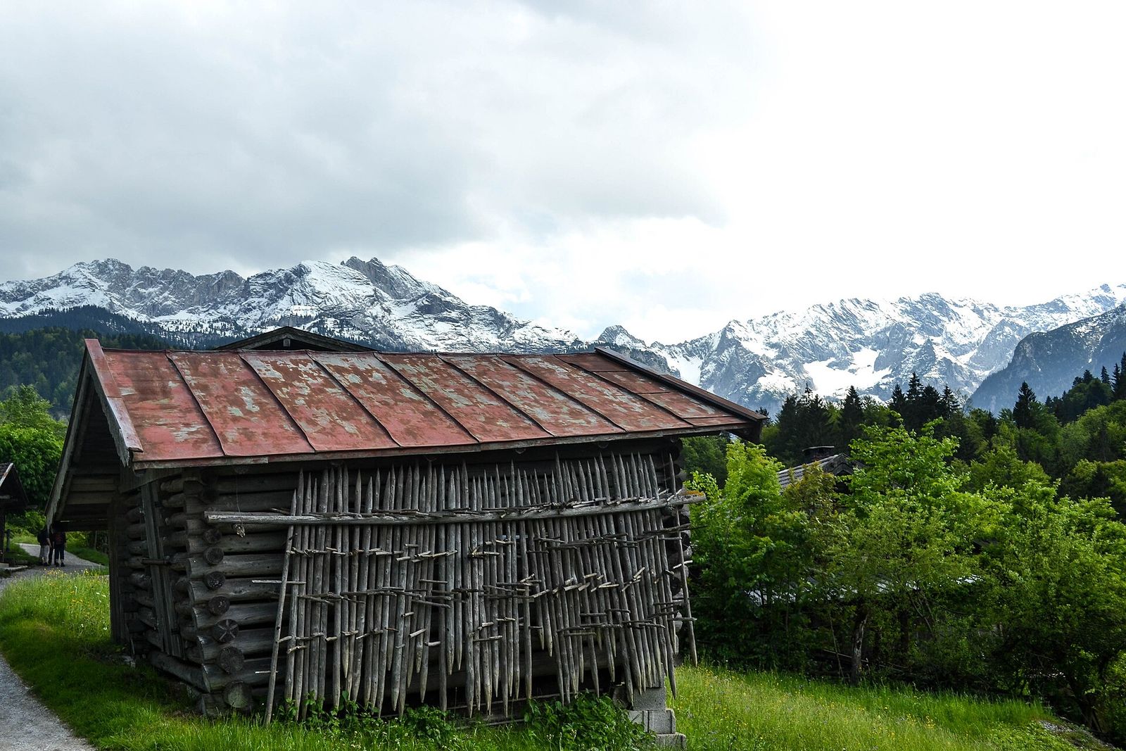 Holzhütte auf einer Almwiese vor schneebedeckten Gipfeln