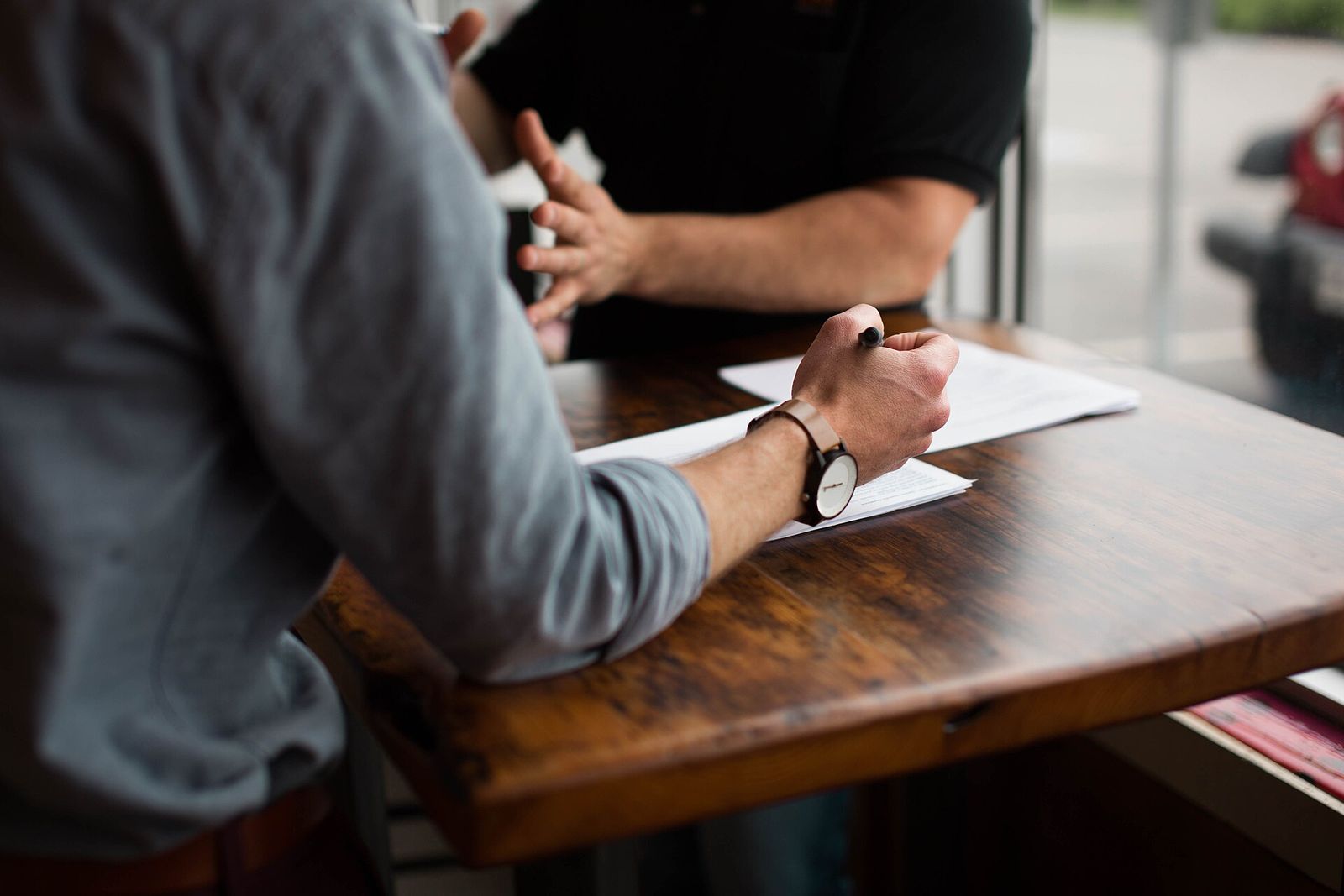 Two people at a desk, one filling in documents