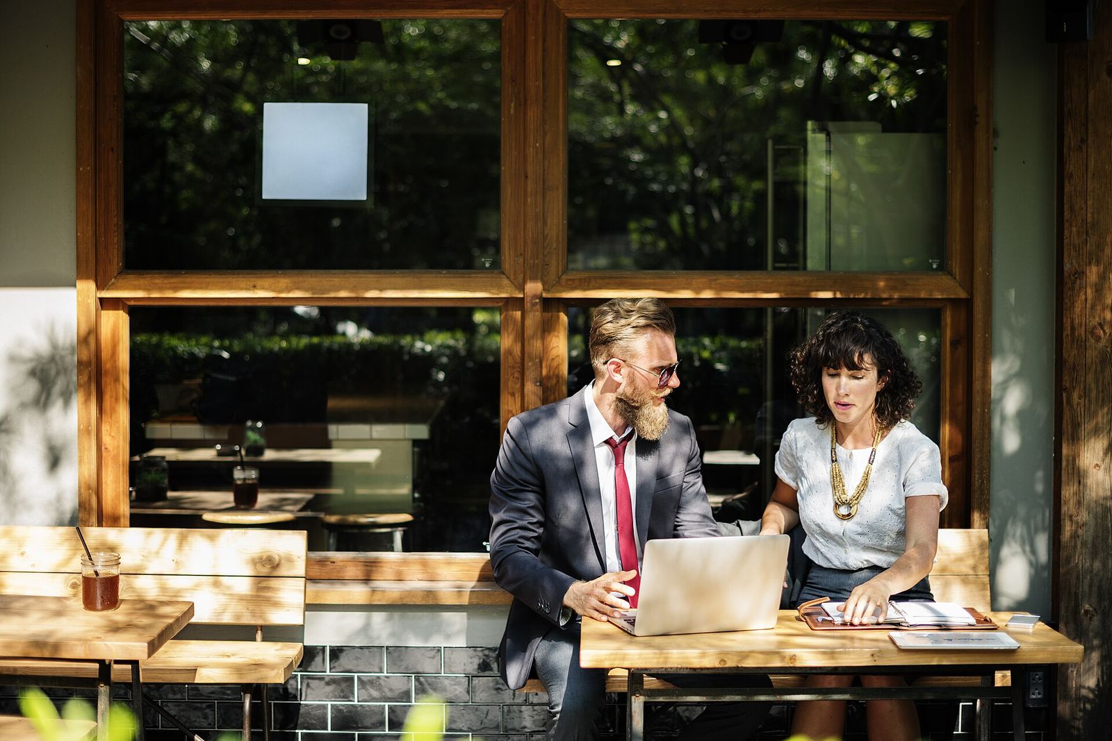 Two colleagues discussing at a laptop in front of a large window